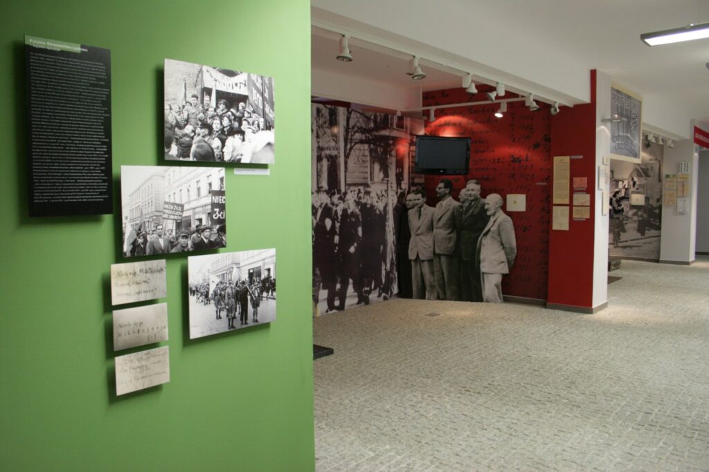 Fragment ekspozycji z archiwalnymi fotografiami oraz planszami opisującymi wydarzenia przedstawione na wystawie (kliknięcie powiększy zdjęcie).