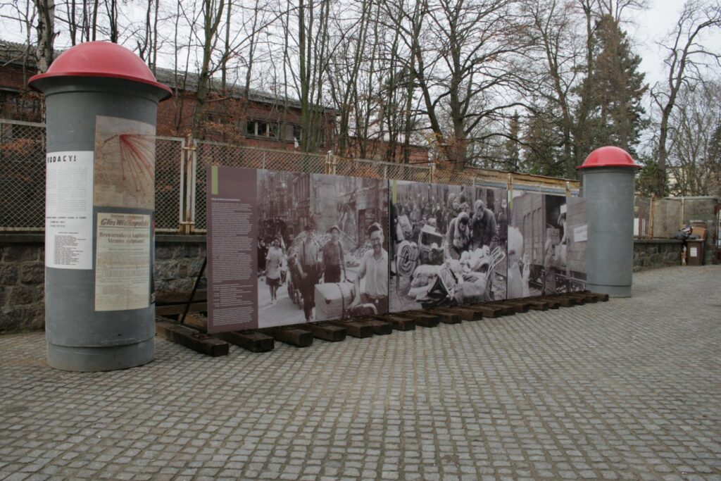 Widok zewnętrznej części wystawy z wielkoformatowymi fotografiami i planszami historycznymi ustawionymi w przestrzeni muzealnej (kliknięcie powiększy zdjęcie).