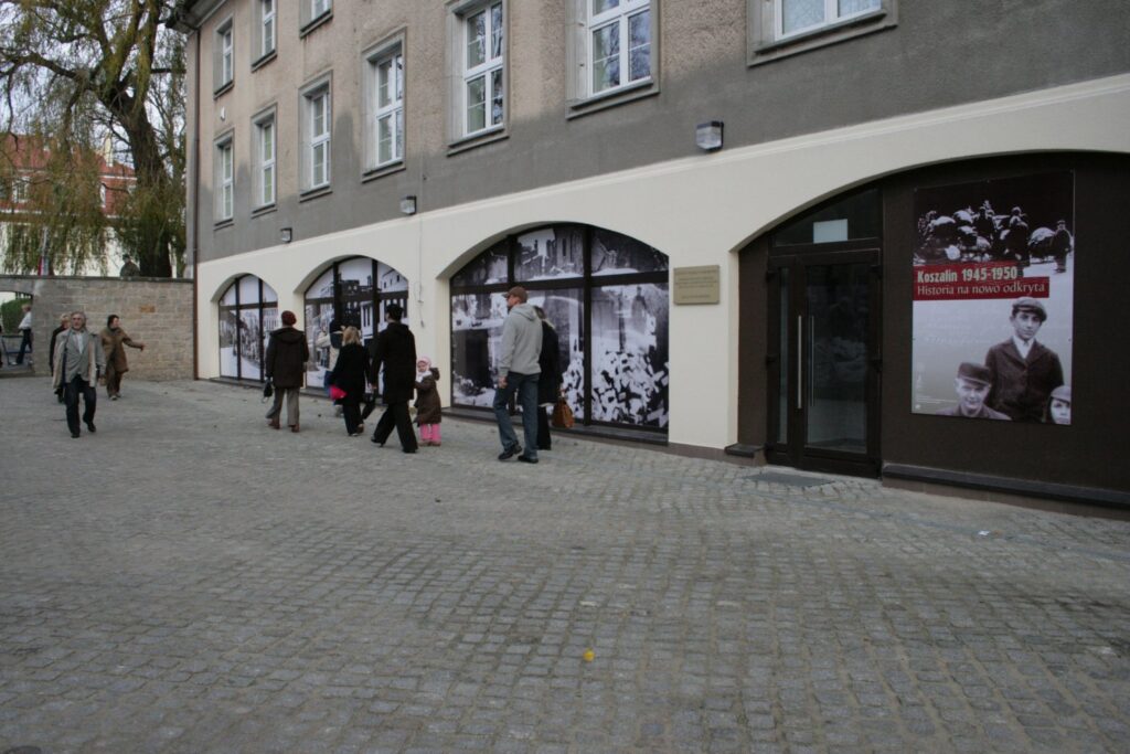 Budynek, w którym odbywa się wystawa, widoczny z zewnątrz, fragmenty ekspozycji prezentowane w oknach sal wystawowych (kliknięcie powiększy zdjęcie).