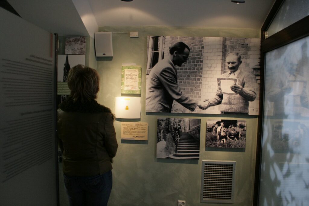 Kobieta ogląda fragment ekspozycji z archiwalnymi fotografiami i materiałami poświęconymi historii miasta (kliknięcie powiększy zdjęcie).