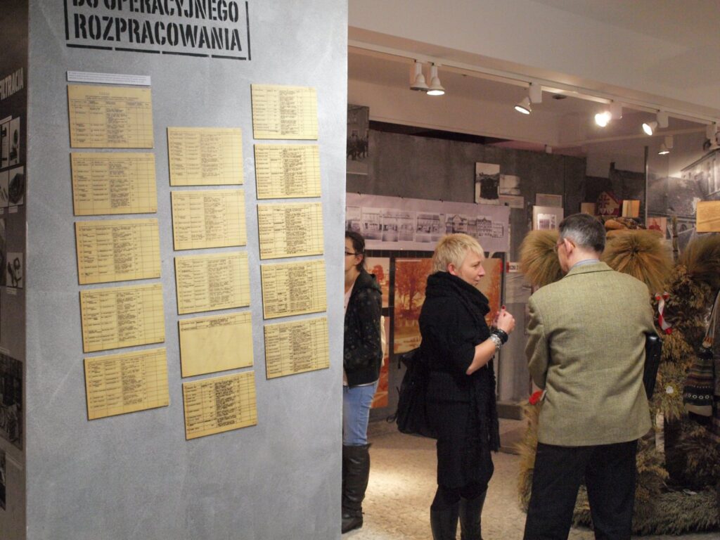 Zwiedzający oglądają planszę z archiwalnymi dokumentami prezentowanymi na wystawie (kliknięcie powiększy zdjęcie).