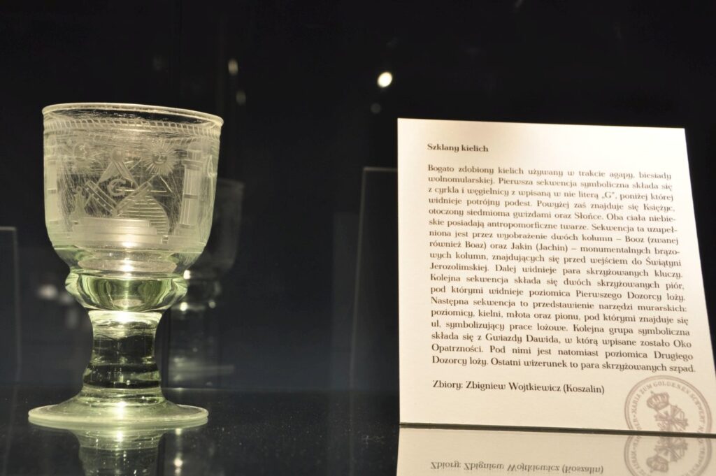 Szklany kielich prezentowany w gablocie wraz z opisem historycznym dotyczącym eksponatu (kliknięcie powiększy zdjęcie).