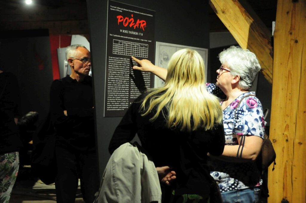 Zwiedzający zapoznający się z treścią planszy opisowej prezentującej historię wydarzeń ukazanych na wystawie (kliknięcie powiększy zdjęcie).