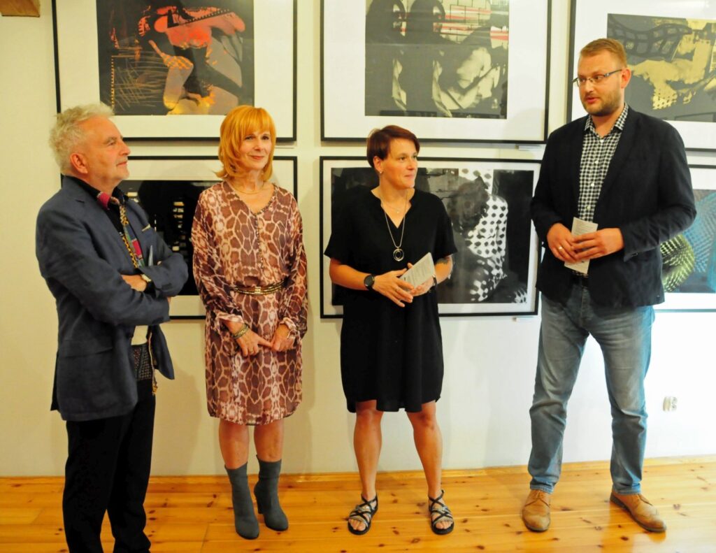 Przedstawiciel muzeum oraz organizatorzy otwierają wystawę sztuki współczesnej, stojąc na tle wielkoformatowych grafik i fotografii prezentowanych w galerii (kliknięcie powiększy zdjęcie).