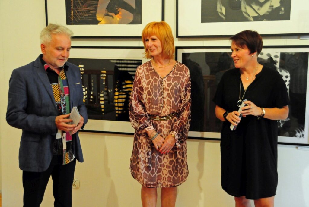 Organizatorzy wydarzenia rozmawiają podczas otwarcia wystawy na tle wielkoformatowych prac graficznych (kliknięcie powiększy zdjęcie).