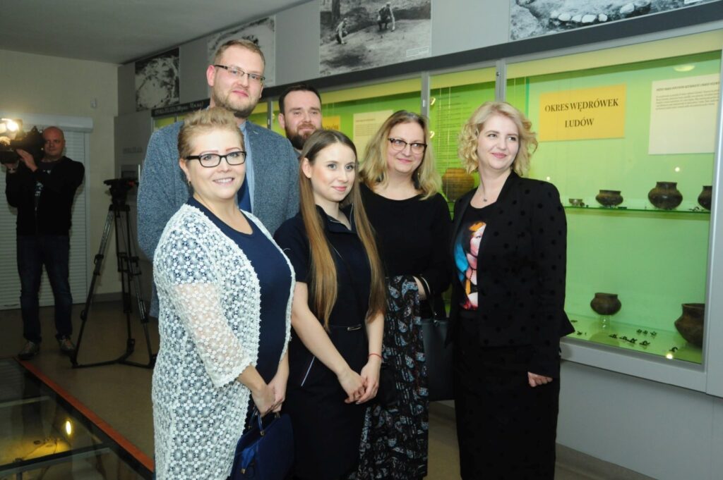 Pamiątkowe zdjęcie organizatorów, kuratorów i współpracowników wystawy wykonane przed gablotami z zabytkami archeologicznymi prezentowanymi na ekspozycji (kliknięcie powiększy zdjęcie).