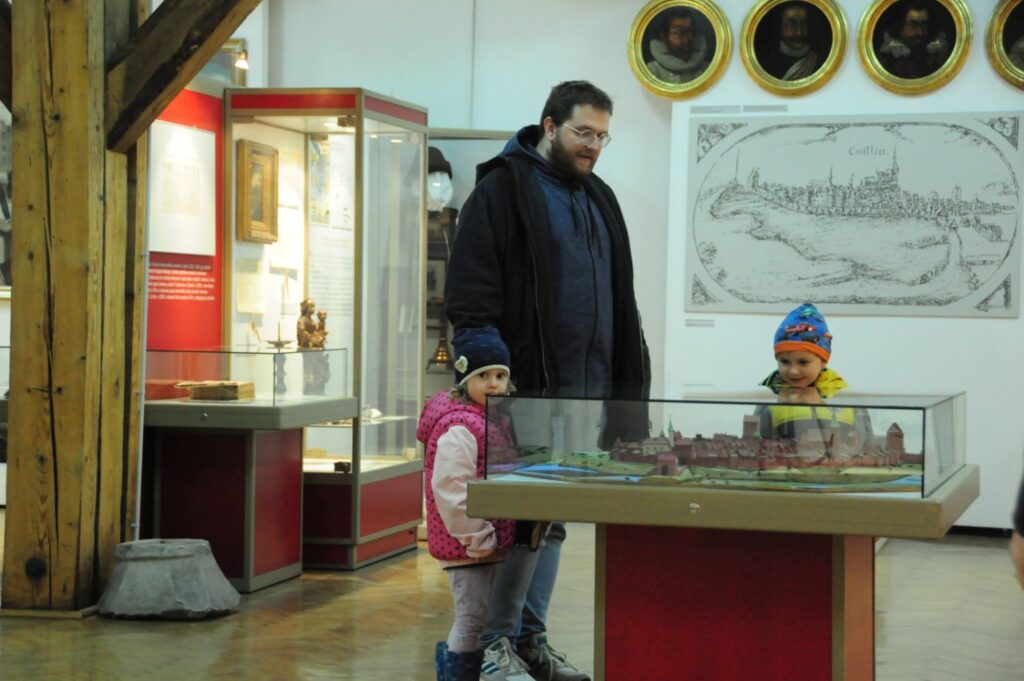 Mężczyzna z dzieckiem ogląda makietę historyczną miasta umieszczoną w przeszklonej gablocie (kliknięcie powiększy zdjęcie).