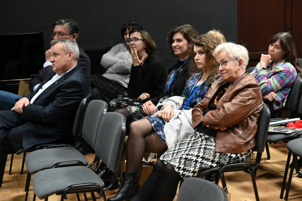 Uczestnicy konferencji siedzą na widowni i słuchają prezentacji naukowej (kliknięcie powiększy zdjęcie).