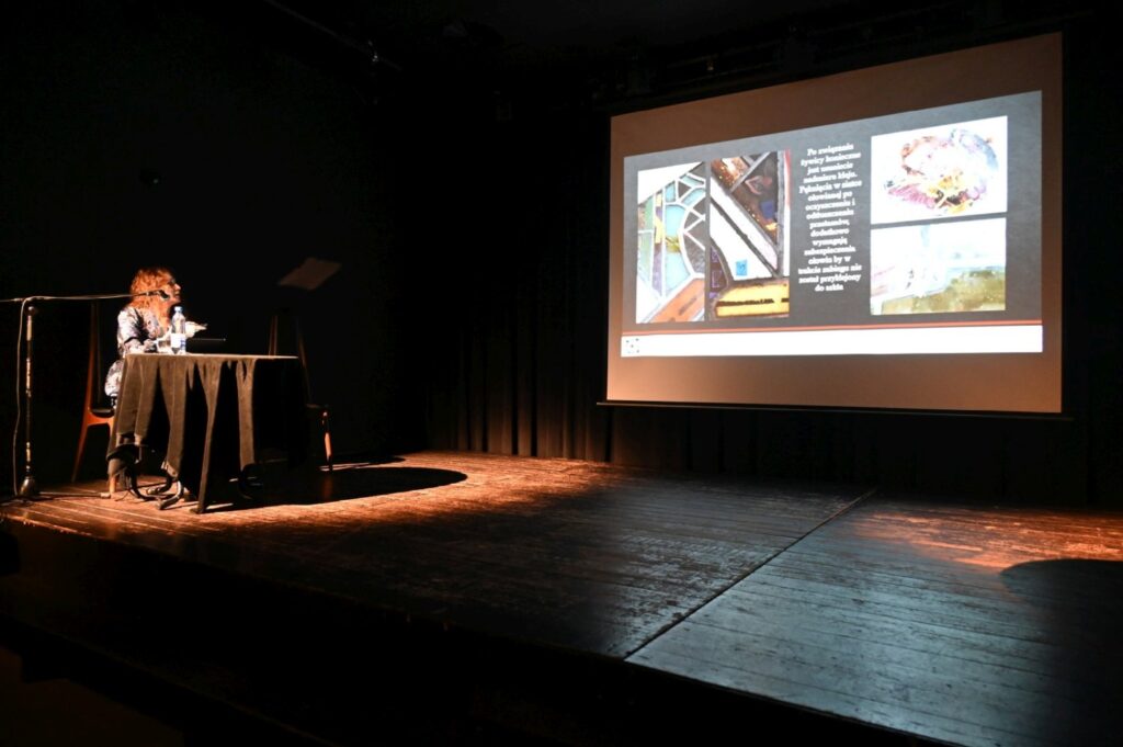 Widok sceny konferencyjnej z prezentacją multimedialną wyświetlaną na dużym ekranie (kliknięcie powiększy zdjęcie).