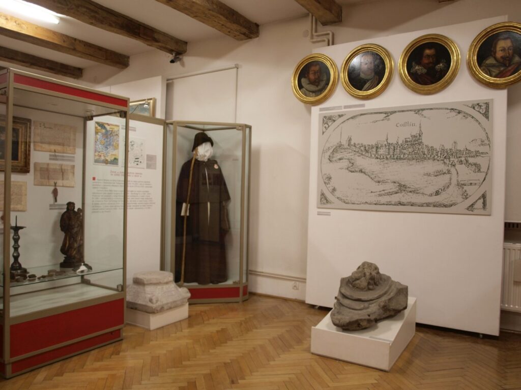 Sala wystawowa z gablotami zawierającymi historyczne przedmioty i dokumenty; na ścianach prezentowane są portrety, mapa oraz reprodukcje dawnych widoków miasta (kliknięcie powiększy zdjęcie).