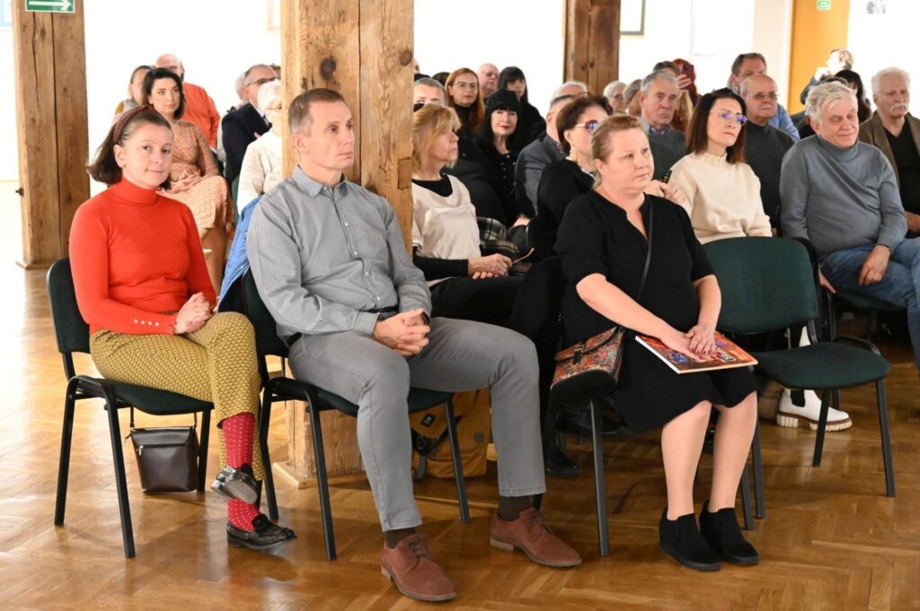 Publiczność siedząca w pierwszym rzędzie uważnie słucha prelekcji podczas wydarzenia (kliknięcie powiększy zdjęcie).