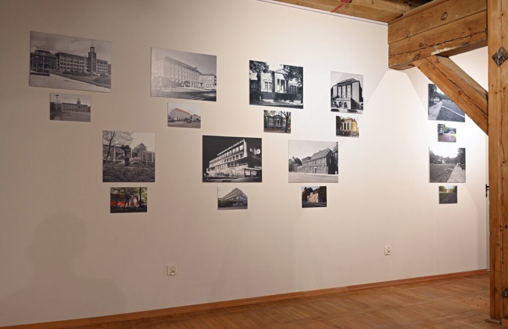 Na jasnej ścianie zaprezentowano kilkanaście fotografii przedstawiających budynki, fragmenty architektury i miejskie przestrzenie; czarno-białe oraz kolorowe fotografie rozmieszczono w kilku grupach o nieregularnym układzie, a po prawej stronie znajduje się kolejny zestaw zdjęć (kliknięcie powiększy zdjęcie).