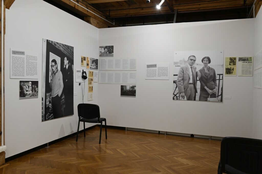Sala wystawowa z dokumentacją fotograficzną i materiałami tekstowymi; na ścianach widoczne są czarno-białe fotografie przedstawiające osoby podczas różnych wydarzeń oraz rozmieszczone między nimi teksty i reprodukcje dokumentów (kliknięcie powiększy zdjęcie).