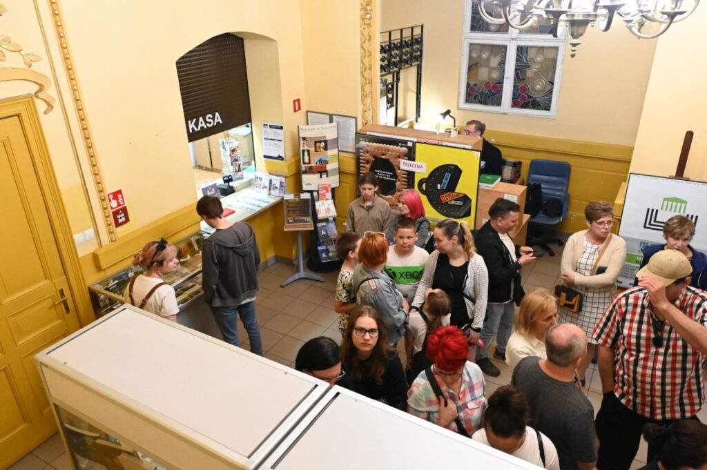 Tłum zwiedzających stoi w korytarzu muzeum i ogląda materiały informacyjne podczas Nocy Muzeów (kliknięcie powiększy zdjęcie).