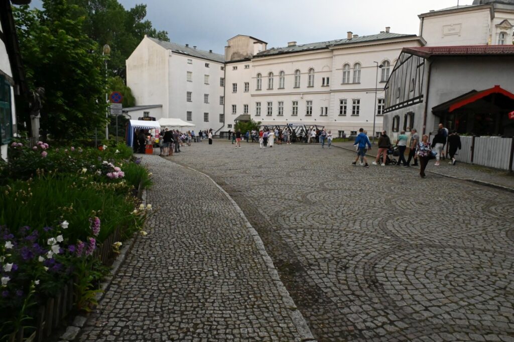 Dziedziniec muzeum z brukowaną nawierzchnią, po którym spacerują uczestnicy wydarzenia podczas Nocy Muzeów (kliknięcie powiększy zdjęcie).