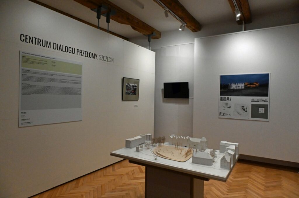 Sala z wystawą poświęconą architekturze i przestrzeni miejskiej; na ścianie widoczny jest napis „CENTRUM DIALOGU PRZEMYSŁOWEGO SZCZECIN”; obok znajdują się fotografie i materiały informacyjne, a na pierwszym planie makieta (kliknięcie powiększy zdjęcie).