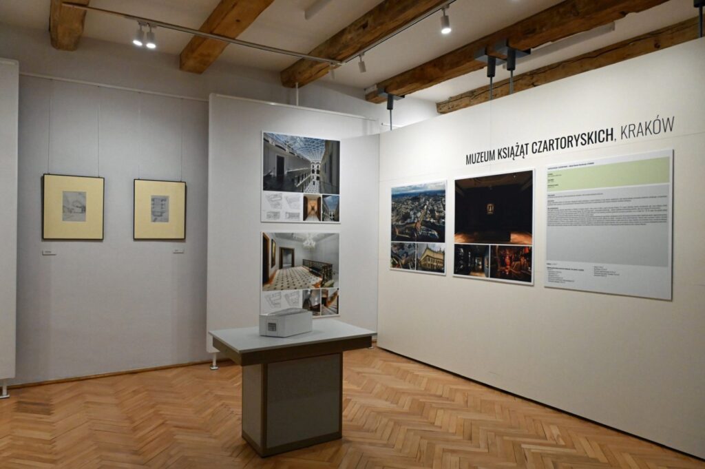Fragment ekspozycji z napisem „MUZEUM KSIĄŻĄT CZARTORYSKICH, KRAKÓW”; na ścianach prezentowane są fotografie, reprodukcje i teksty dotyczące muzeum; przed ekspozycją ustawiono stół z makietą (kliknięcie powiększy zdjęcie).