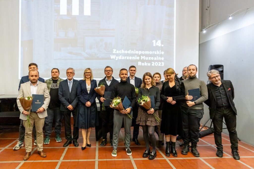 Duża grupa nagrodzonych i organizatorów pozuje do wspólnego zdjęcia na scenie podczas gali (kliknięcie powiększy zdjęcie).