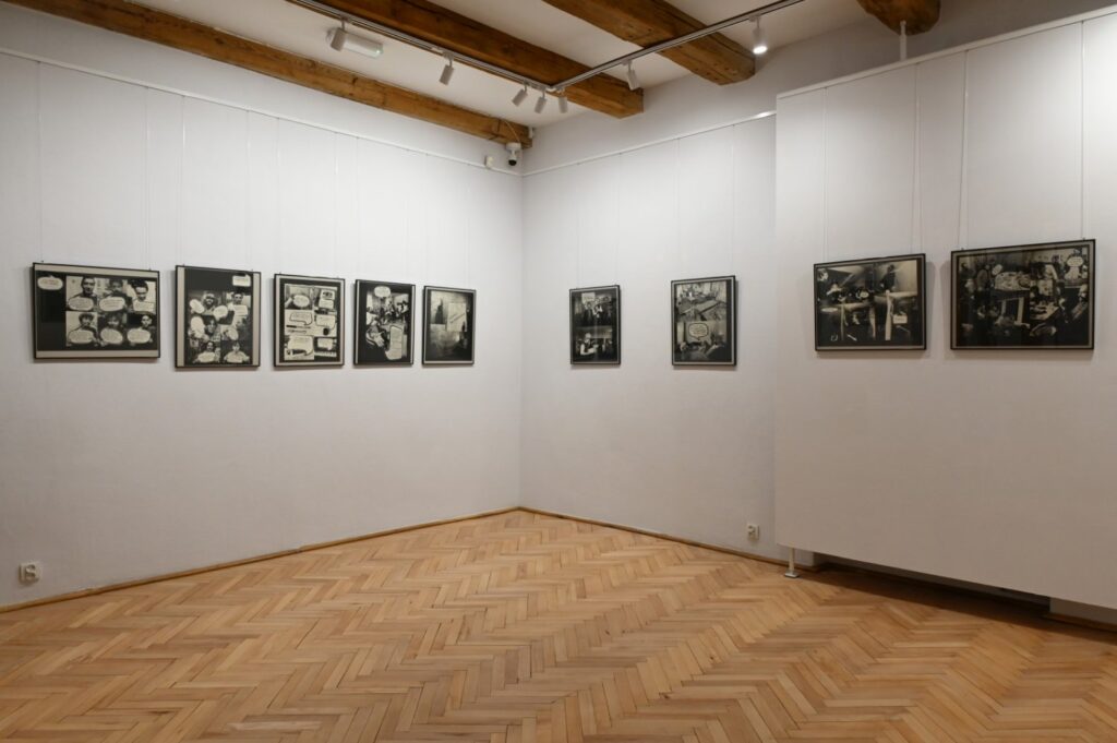 Sala wystawowa z serią czarno-białych prac graficznych i fotograficznych rozmieszczonych na dwóch ścianach; na środku pozostawiono wolną przestrzeń do zwiedzania (kliknięcie powiększy zdjęcie).