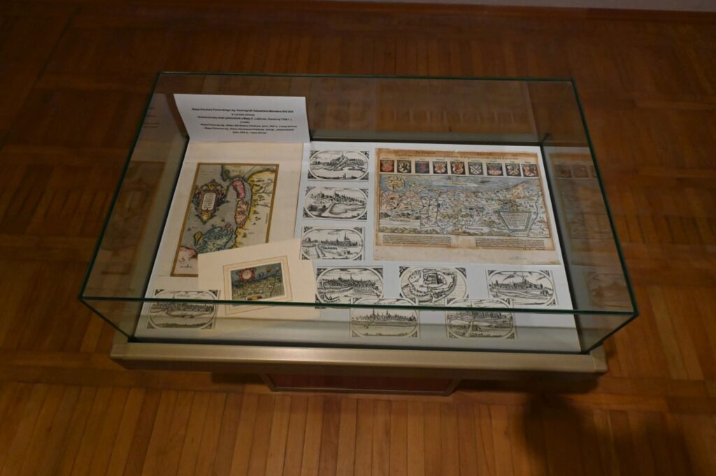 Gablota prezentująca materiały drukowane i graficzne związane z historią oraz kolekcjonerstwem; widoczne są mapy, ilustracje, reprodukcje dokumentów i zestawy niewielkich druków ułożonych na jasnym podłożu; poszczególne materiały zostały rozmieszczone w grupach i opatrzone opisami, tworząc uporządkowaną ekspozycję dokumentującą wybrane zagadnienie historyczne (kliknięcie powiększy zdjęcie).