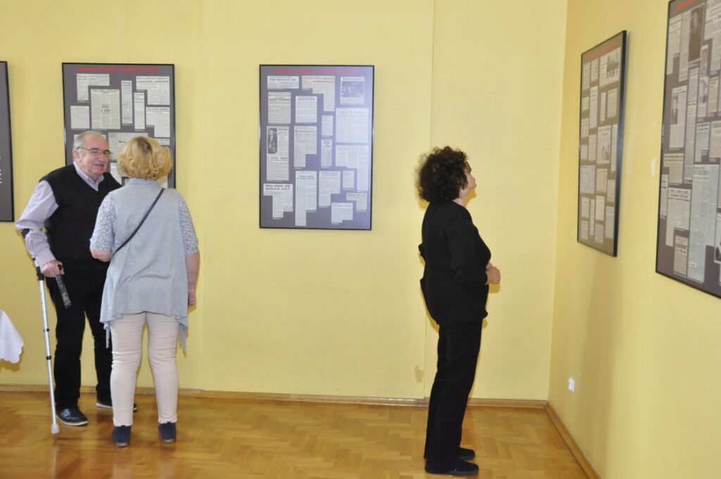 Widok sali ekspozycyjnej z planszami prezentującymi dokumenty oraz zwiedzającymi oglądającymi wystawę (kliknięcie powiększy zdjęcie).