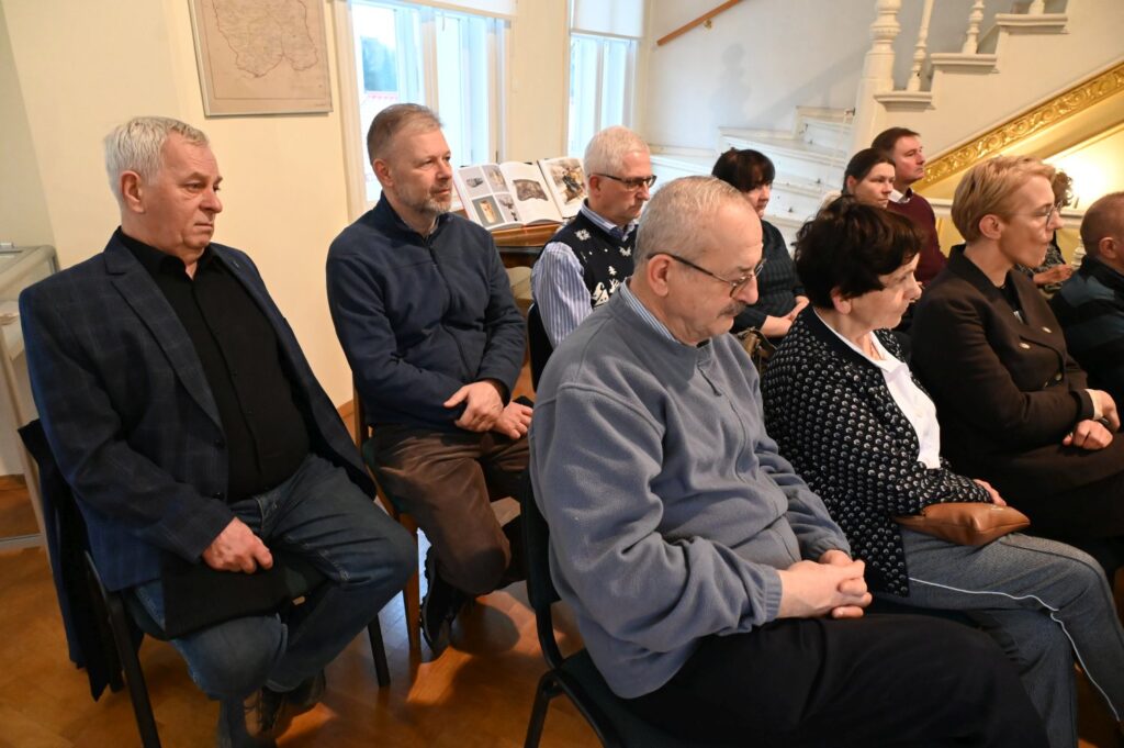 Uczestnicy wydarzenia podczas spotkania w muzealnej sali, publiczność siedzi na krzesłach i słucha prowadzących; w tle widoczne są elementy wystroju wnętrza oraz fragmenty ekspozycji (kliknięcie powiększy zdjęcie).