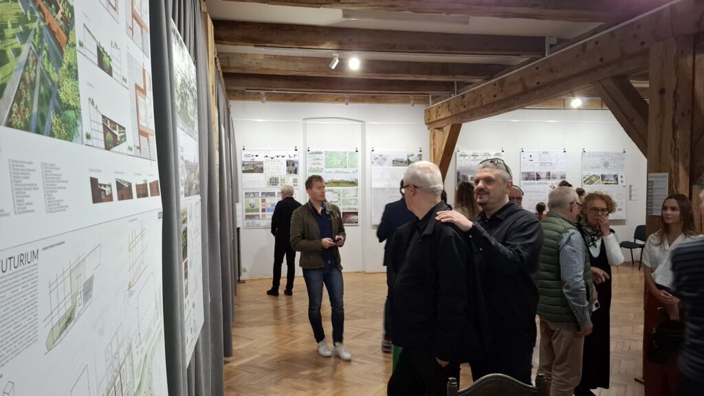 Uczestnicy oglądający plansze wystawowe z projektami architektonicznymi w galerii (kliknięcie powiększy zdjęcie).