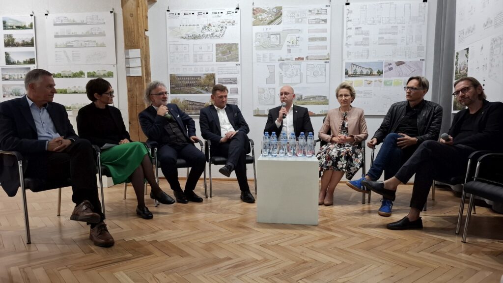 Panel dyskusyjny z udziałem kilku osób siedzących przy stole, prowadzących rozmowę przed publicznością (kliknięcie powiększy zdjęcie).