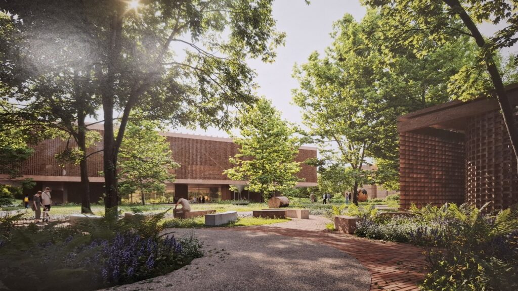 Plansza z wizualizacją: widok na kompleks budynków z ceglaną architekturą, otoczony zielenią, ścieżkami i roślinnością; przez drzewa prześwieca światło (kliknięcie powiększy zdjęcie).