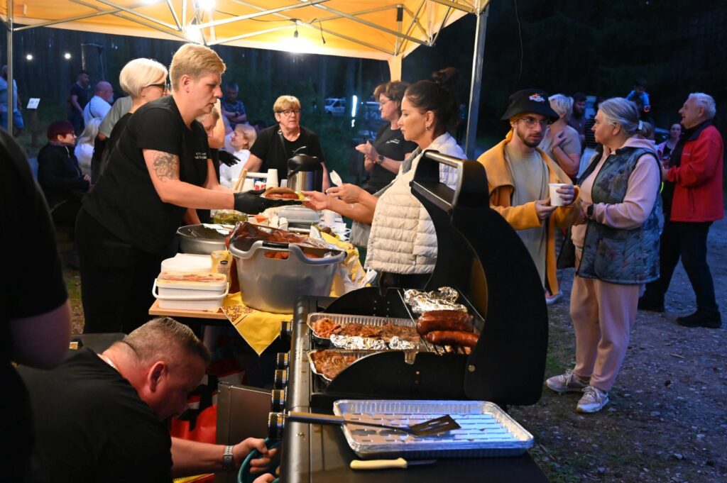 Stoisko gastronomiczne pod namiotem, gdzie uczestnicy Nocy Gotów odbierają posiłki przygotowywane na grillu (kliknięcie powiększy zdjęcie).