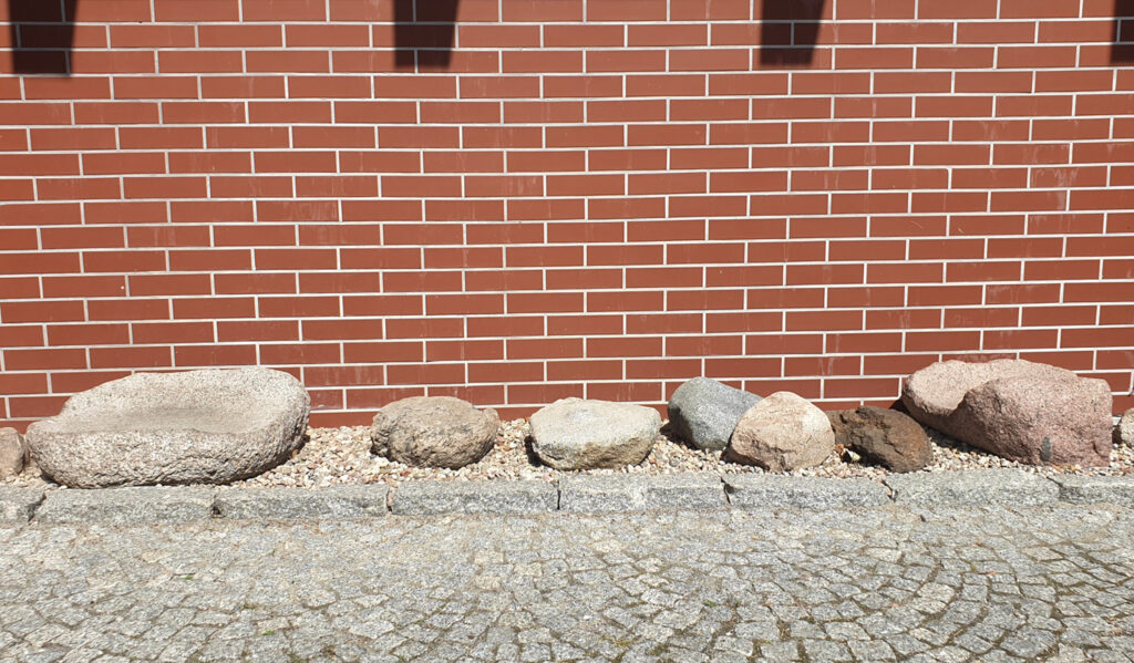 Ustawione przez ścianą imitująca czerwoną cegłę, nieckowate i rotacyjne żarna (kliknięcie spowoduje powiększenie zdjęcia).
