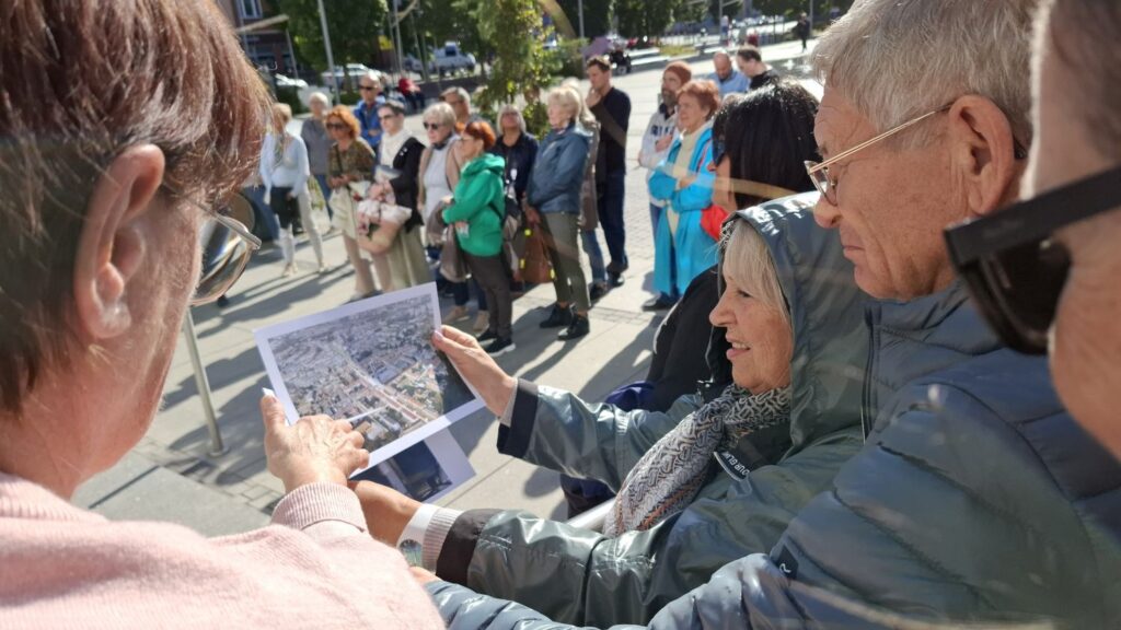 Uczestnicy spaceru historycznego oglądają archiwalne zdjęcie przedstawiające Ratusz (kliknięcie powiększy zdjęcie).