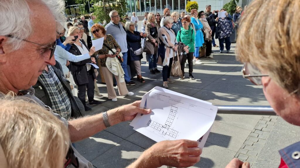Uczestnicy spaceru analizują rysunek techniczny związany z historią Ratusza (kliknięcie powiększy zdjęcie).