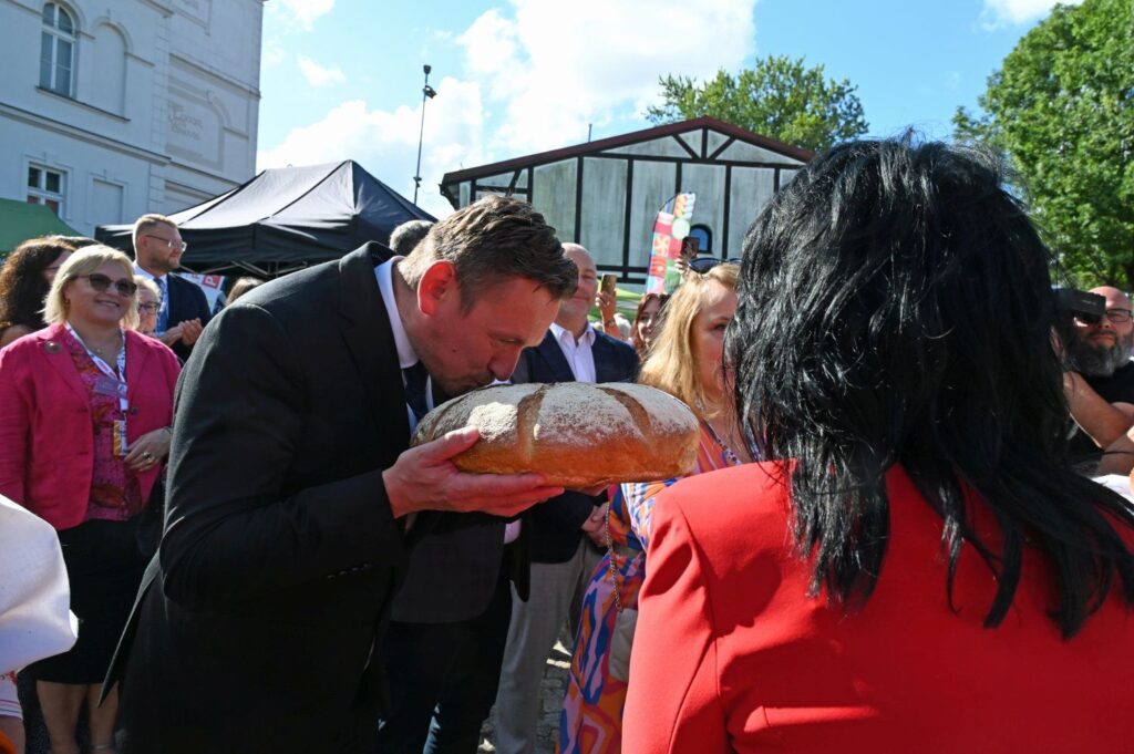 Mężczyzna pochylający się nad bochnem chleba w geście tradycyjnego powitania (kliknięcie powiększy zdjęcie).