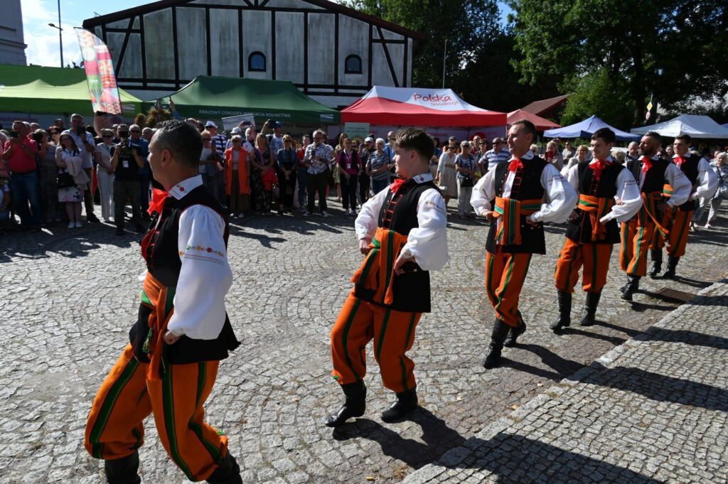 Tancerze w strojach regionalnych prezentujący układ taneczny na dziedzińcu wśród zgromadzonej publiczności (kliknięcie powiększy zdjęcie).