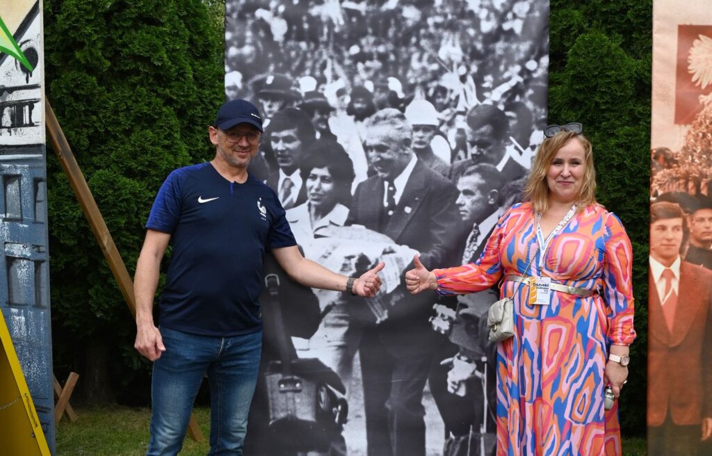 Dwie osoby stojące przy archiwalnej fotografii, nawiązującej do historii wydarzenia dożynkowego (kliknięcie powiększy zdjęcie).