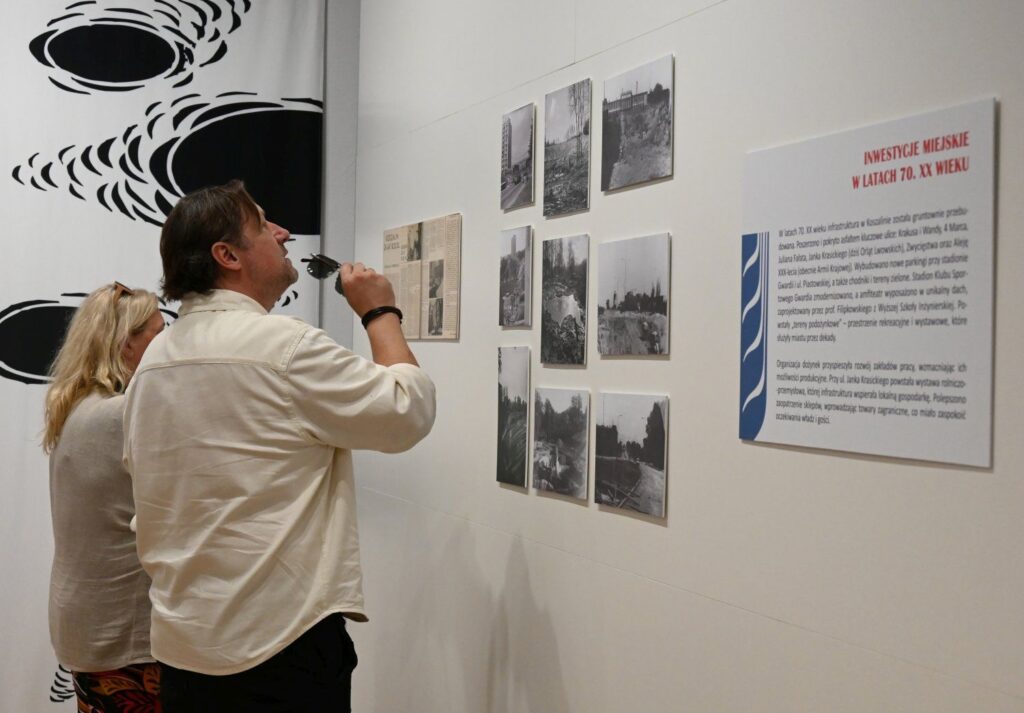 Zwiedzający oglądający archiwalne fotografie i plansze informacyjne na wystawie muzealnej (kliknięcie powiększy zdjęcie).