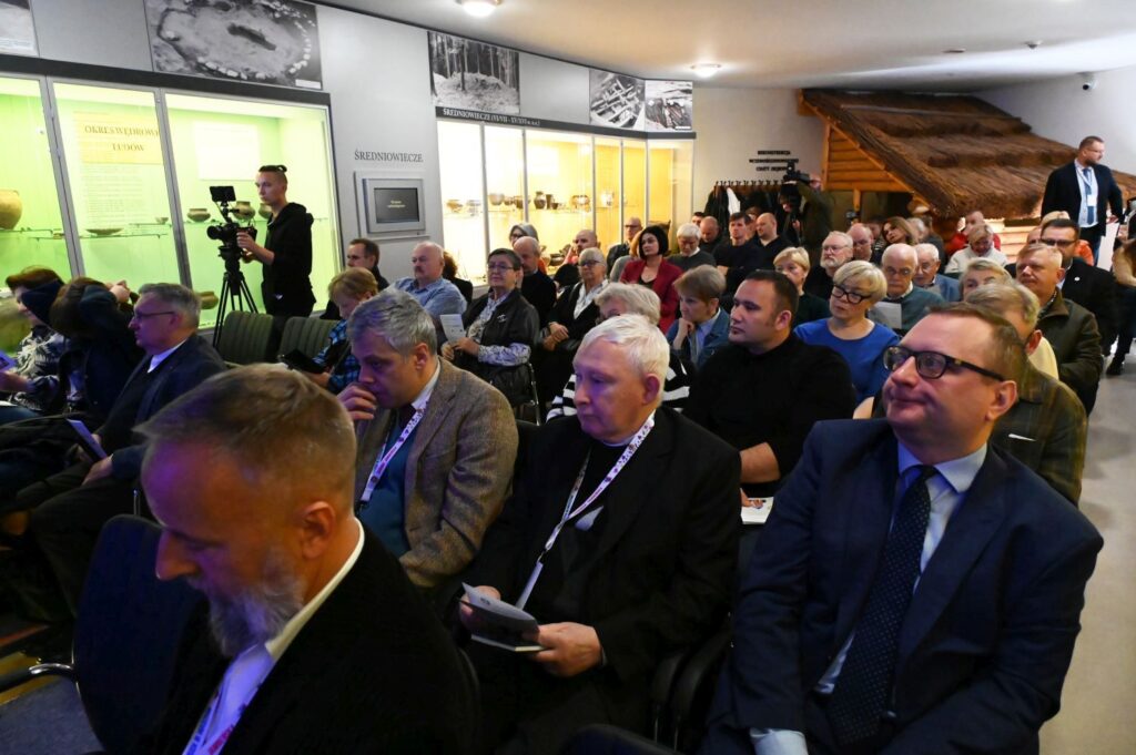 Uczestnicy konferencji siedzą na sali i słuchają prelekcji w przestrzeni wystawowej muzeum (kliknięcie powiększy zdjęcie).
