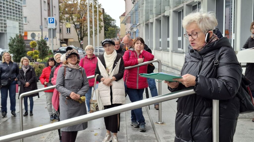 Przewodniczka czyta materiały uczestnikom spaceru historycznego przed budynkiem Ratusza (kliknięcie powiększy zdjęcie).