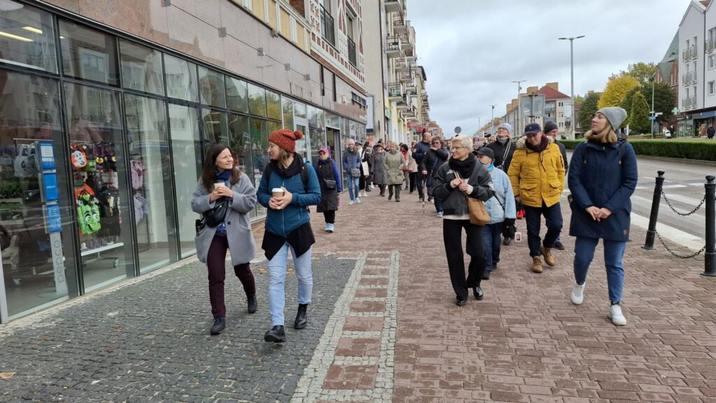 Grupa uczestników spaceru historycznego przechodzi ulicą miasta podczas zwiedzania (kliknięcie powiększy zdjęcie).