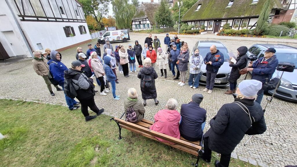 Grupa uczestników spaceru historycznego zgromadzona na dziedzińcu muzeum podczas opowieści o historii miejsca (kliknięcie powiększy zdjęcie).