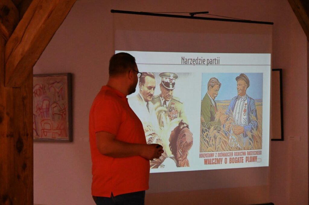 Prelegent omawia slajd z materiałami historycznymi podczas wykładu (kliknięcie powiększy zdjęcie).