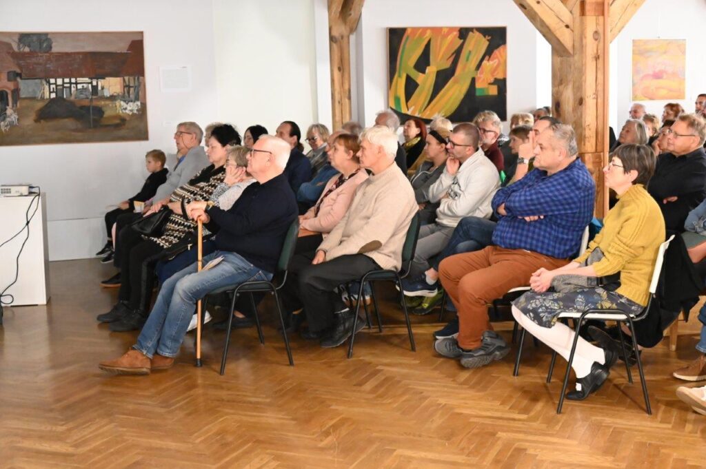 Publiczność zgromadzona w sali muzealnej uważnie słucha wykładu o historii (kliknięcie powiększy zdjęcie).