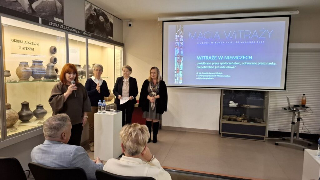 Prelegentka przemawia do publiczności podczas spotkania o witrażach, w tle prezentacja multimedialna na ekranie (kliknięcie powiększy zdjęcie).