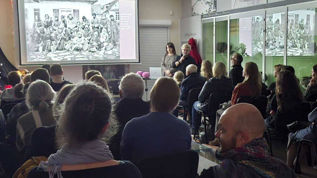 Uczestnicy spotkania oglądający na ekranie ilustrację historycznej sceny, w trakcie wykładu poświęconego tradycjom związanym z Halloween (kliknięcie powiększy zdjęcie)