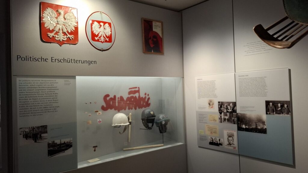 Ekspozycja muzealna poświęcona historii politycznej, z hełmami, dokumentami i fotografiami oraz godłem państwa polskiego (kliknięcie powiększy zdjęcie)
