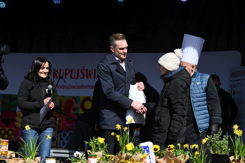 Organizator wręcza nagrodę uczestnikowi na scenie w trakcie konkursu kulinarnego (kliknięcie powiększy zdjęcie).