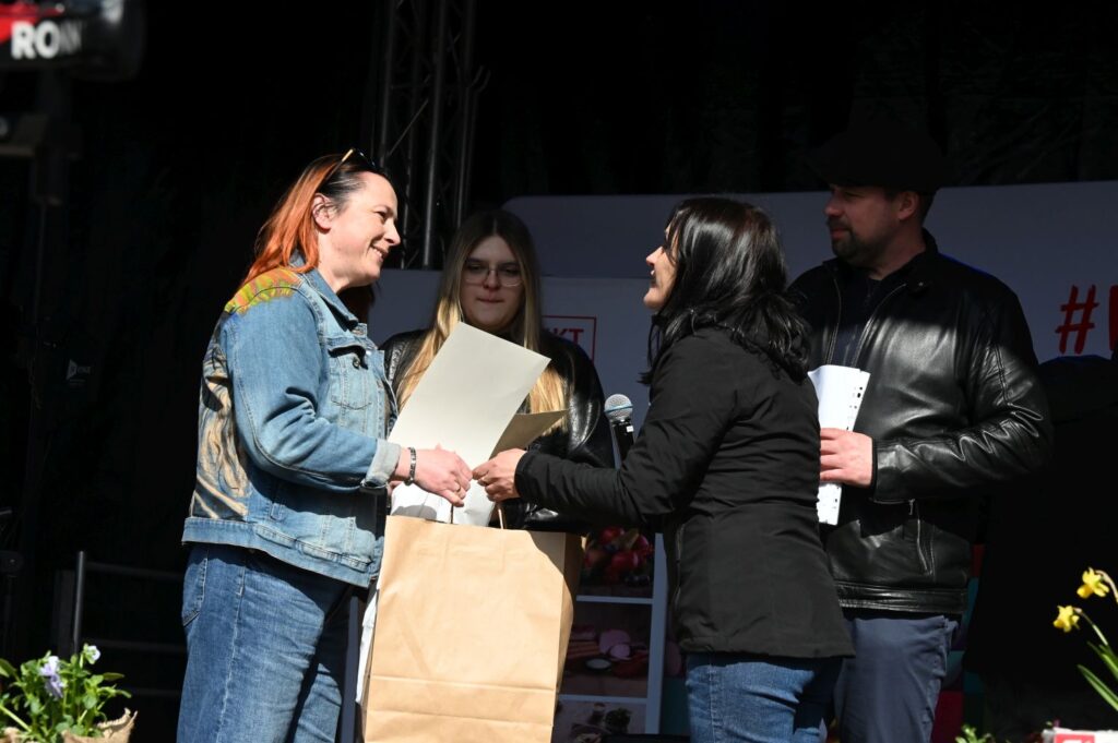 Kobieta odbiera nagrodę i torbę z upominkami od organizatorów konkursu (kliknięcie powiększy zdjęcie).