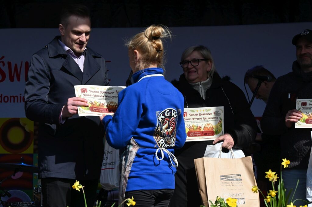 Młoda uczestniczka konkursu odbiera dyplom i nagrodę podczas wręczenia wyróżnień (kliknięcie powiększy zdjęcie).