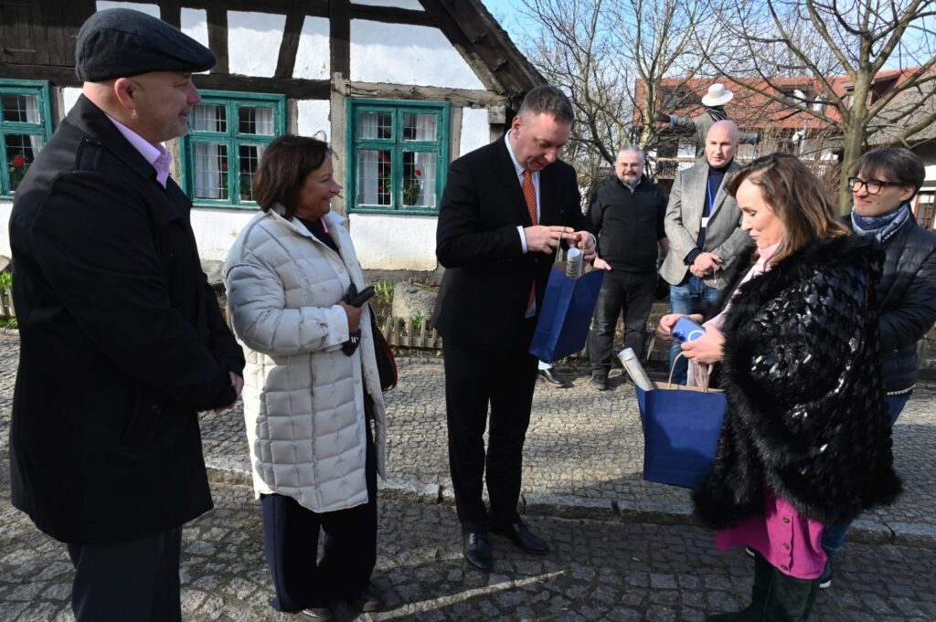 Wręczanie upominków podczas wizyty w muzeum, w tle zabytkowa chałupa rybaka (kliknięcie powiększy zdjęcie).
